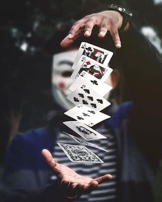 a person wearing a mask holding playing cards in front of their face with both hands