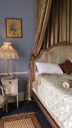 a bed sitting in a bedroom next to a table with a lamp on top of it