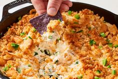 a person dipping a tortilla chip into a skillet