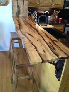 a wooden table sitting in the middle of a kitchen next to a counter top with two stools