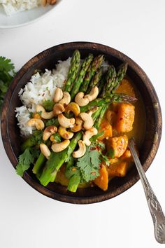 a bowl filled with rice, asparagus and cashews