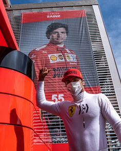 a woman wearing a face mask standing in front of a building with a large poster on it