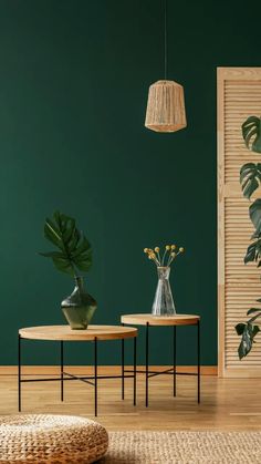 two tables with plants and vases on them in front of a green painted wall