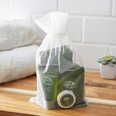 a couple of bags sitting on top of a wooden table next to towels and plants