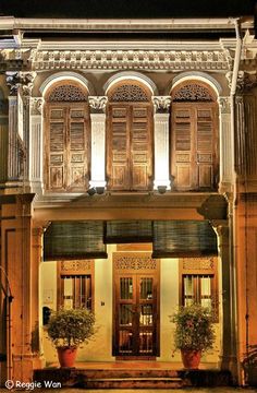 an old building lit up at night with potted plants on the front and side