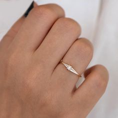 a woman's hand wearing a gold ring with a small diamond on the middle