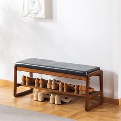 a wooden bench with shoes on it in front of a white wall and hardwood floor