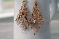 a pair of gold - plated wire earrings on a coffee cup