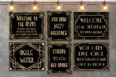 four black and gold art deco style signs hanging on a wall with lights above them