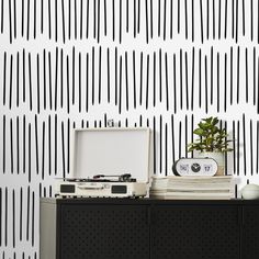 a record player sitting on top of a dresser next to a wall with black and white stripes