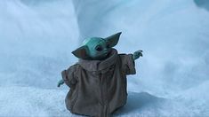 a baby yoda doll sitting in the snow