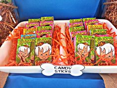 candy sticks with cartoon characters on them in a white tray next to other candies