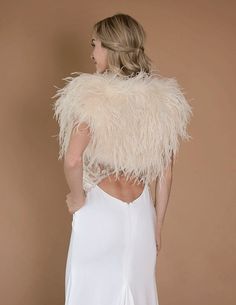 the back of a woman wearing a white dress and ostrich feather shawl