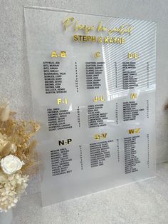 a clear acrylic wedding seating chart with gold lettering on the front and back