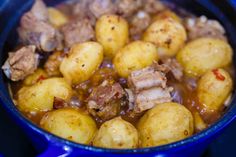 a blue pot filled with meat and potatoes