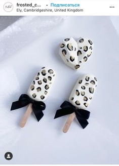 three popsicles with black bows and leopard print are on a white plate next to each other