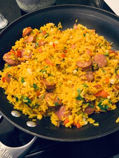 a skillet filled with rice and sausages on top of a stove burner