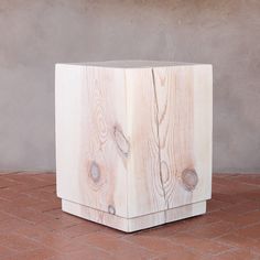 a wooden block sitting on top of a red tile floor next to a cement wall