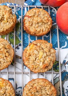 several muffins on a cooling rack with peaches in the backgroud