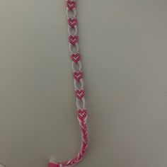 a pink and white rope with two hearts on it hanging from a hook in a bathroom