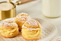 three powdered sugar covered pastries on a plate next to a glass of milk