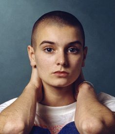 a young man with his hands on his head, posing for a photo in front of a blue background