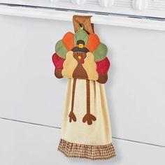 a kitchen towel hanging on the side of a refrigerator door with a turkey applique