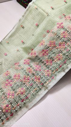 two pieces of cloth are laying next to each other on a white tablecloth with pink and green designs