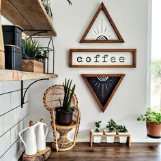 a coffee shop sign hanging on the wall next to a potted plant and wicker chair