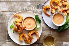 two plates with shrimp and dipping sauces on them