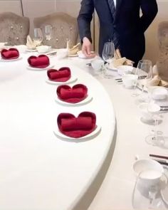 a man in a suit standing next to a table with red velvet hearts on it