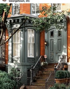 an old building with green doors and steps leading up to the front door is surrounded by greenery