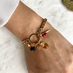 The ÉGYPTE bracelet consists of a gourmet chain, a thick gold-plated circle on which are suspended charm pendants: a point, a star, a patterned circle, a row of two red Swarovski ceramic beads, a night stone chips and a Swarovski golden crystal beetle. There are two tether levels: 15.5cm and 17.5cm. Feel free to ask me by message if you want to adjust the length before ordering. All the golden elements are gold-plated 24K (except the Buddha on this model). The jewels are made entirely by hand in Elegant Metal Chain Bracelet With Dangling Charms, Gold Dangle Chain Bracelet With Charms, Gold Chain Bracelet With Dangle Charms, Gold-plated Dangle Charm Bracelet, Gold Plated Bracelet With Dangling Charms, Gold-plated Charm Bracelets, Gold-plated Bracelets With Charms, Gold-tone Metal Bracelets With Charms, Gold Charm Bracelet With Removable Dangle Charms