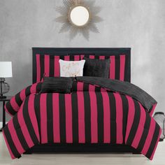 a black and pink striped comforter set on a bed with two lamps next to it