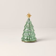 a small green glass christmas tree with a star on it's top sitting on a white surface