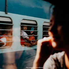 people are looking out the window of a train as it passes by in front of them