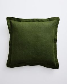 a dark green pillow on a white wall with the bottom half turned to show it's texture