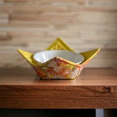 an origami bowl sitting on top of a wooden table