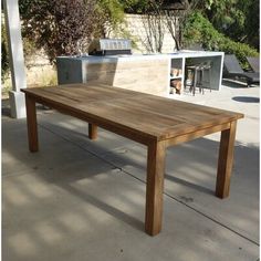 a wooden table sitting in the middle of a patio next to an outdoor bbq