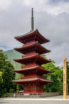 a tall red pagoda sitting in the middle of a forest