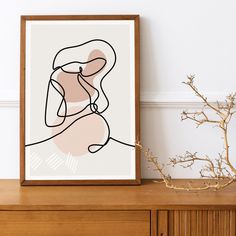 a framed art print on a dresser next to a plant