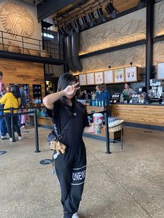 a woman standing in front of a food stand holding her hand up to her face