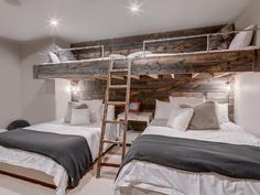 two beds in a room with wooden walls and ladders on the wall above them