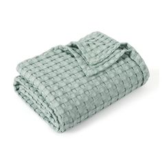 a blanket that is folded up on top of a white surface with a light green checkered pattern