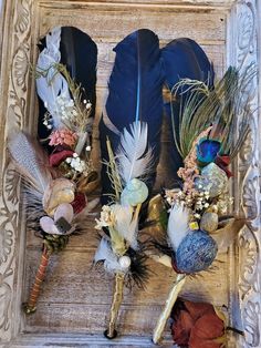 three feathers and flowers are placed in a frame