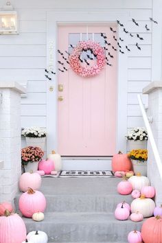 pink and white pumpkins are on the front steps of a house with a wreath