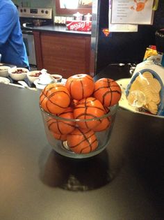 a glass bowl filled with oranges on top of a counter