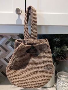 "This purse puts a unique twist on the standard handle. Its chic and simple look is perfect for a project bag or everyday tote. It can be used for a great girl's night out or a day at the park. 7\" Diameter Bottom 8 1/2 \" High without the Handle This purse is made with Lion Brand Rewind Tape Yarn and used the pattern I purchased from The Bokit Store. © 2023 DeBrosse  70% Polyester and 30% Viscose   This is a lovely lightweight sand-washed yarn. Color: Willow Care:  Machine Wash in cool water and should be laid flat to air-dry." Versatile Crochet Shoulder Bag, Versatile Everyday Crochet Shoulder Bag, Versatile Crochet Shoulder Bag For Everyday, Beige Crochet Bucket Bag With Top Carry Handle, Beige Handheld Bucket Bag For Everyday, Handheld Beige Bucket Bag For Everyday, Everyday Crochet Bucket Bag With Top Handle, Everyday Bucket Crochet Bag With Top Handle, Everyday Crochet Bucket Bag With Top Carry Handle