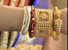 two women wearing bracelets on their arm with gold and red jewelry in the background