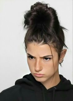 a woman with a messy topknot and black hoodie looking at the camera